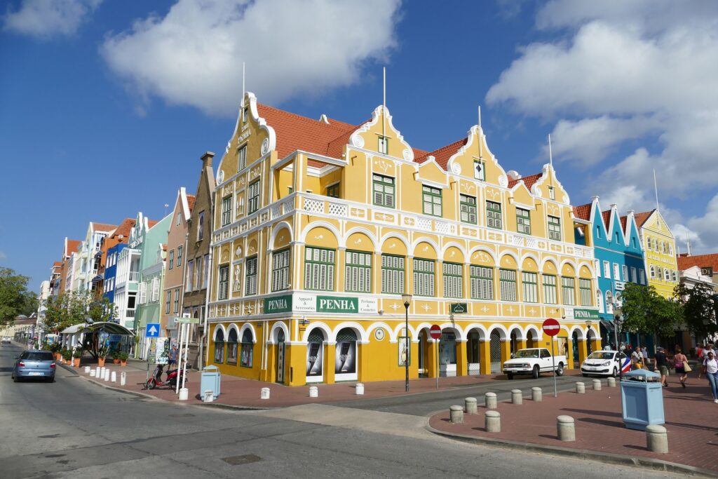 a yellow heritage building in curacao which is stunning to look at with red roof