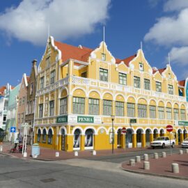 a yellow heritage building in curacao which is stunning to look at with red roof