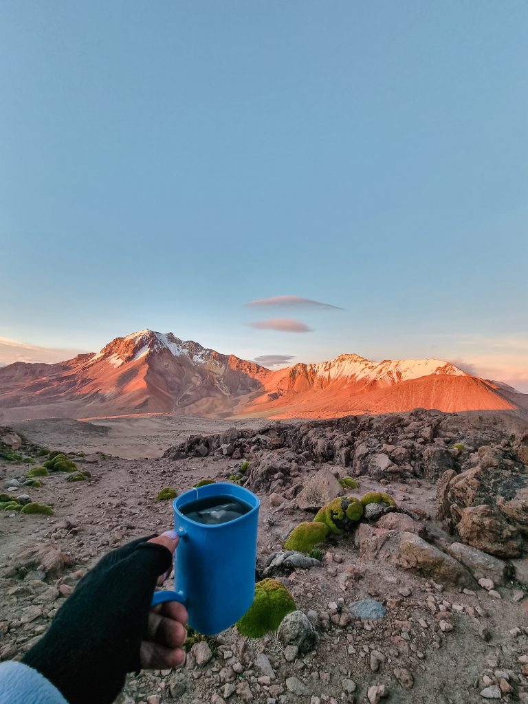 hand holding a blue cup infront of a Chachani volcanic mountain in Peru