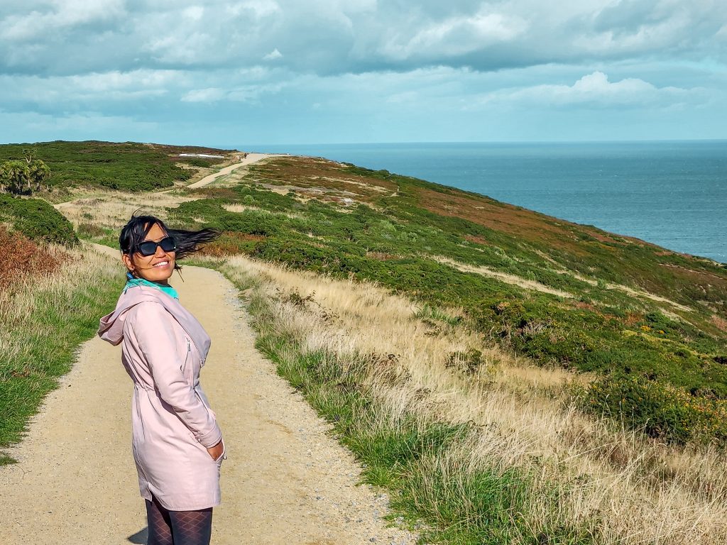 girl on a pink jacket walking on a howth cliff walk - dublin to howth