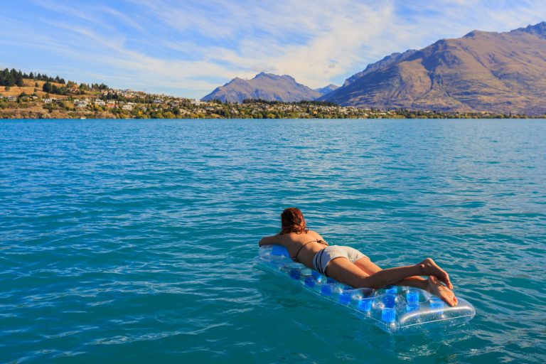 young adult women enjoy floating on a mattress in Queensland's natural lake, New zealand